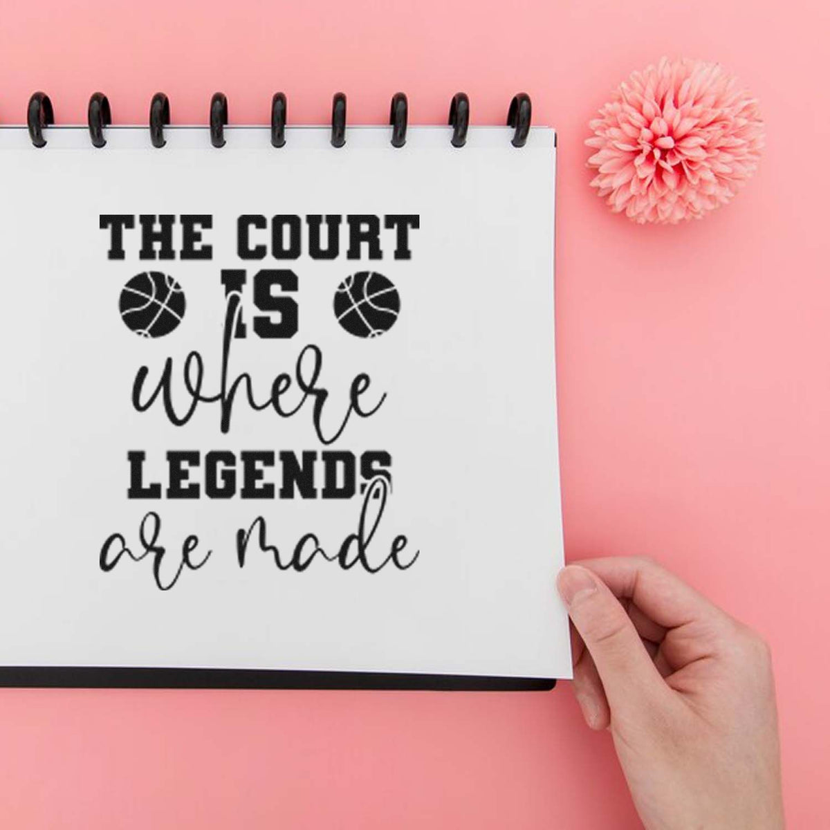 Basketball stamp and seal design on white notebook, black text reading The court is where legends are made on pink background.