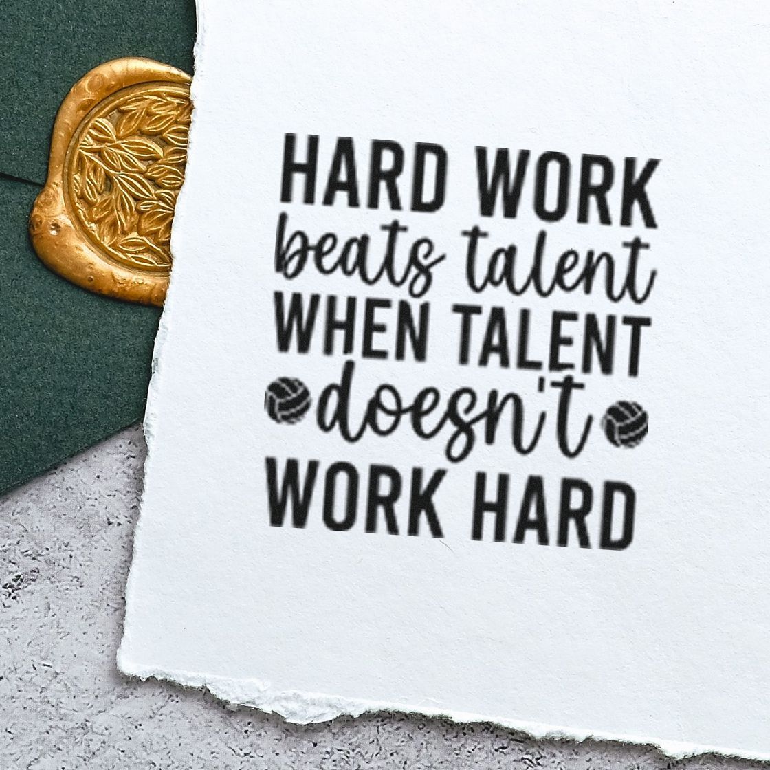 Black motivational rubber stamp on torn white paper beside a gold embossed wax seal on dark green background.