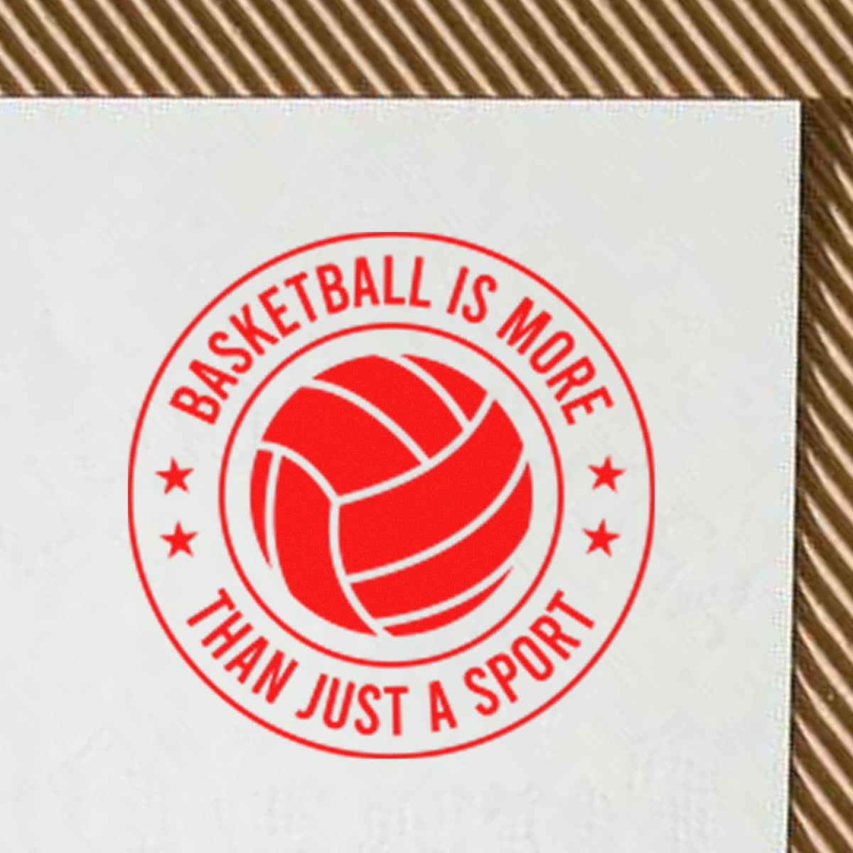 Red circular stamp seal with ball icon and text Basketball Is More Than Just A Sport on white paper.