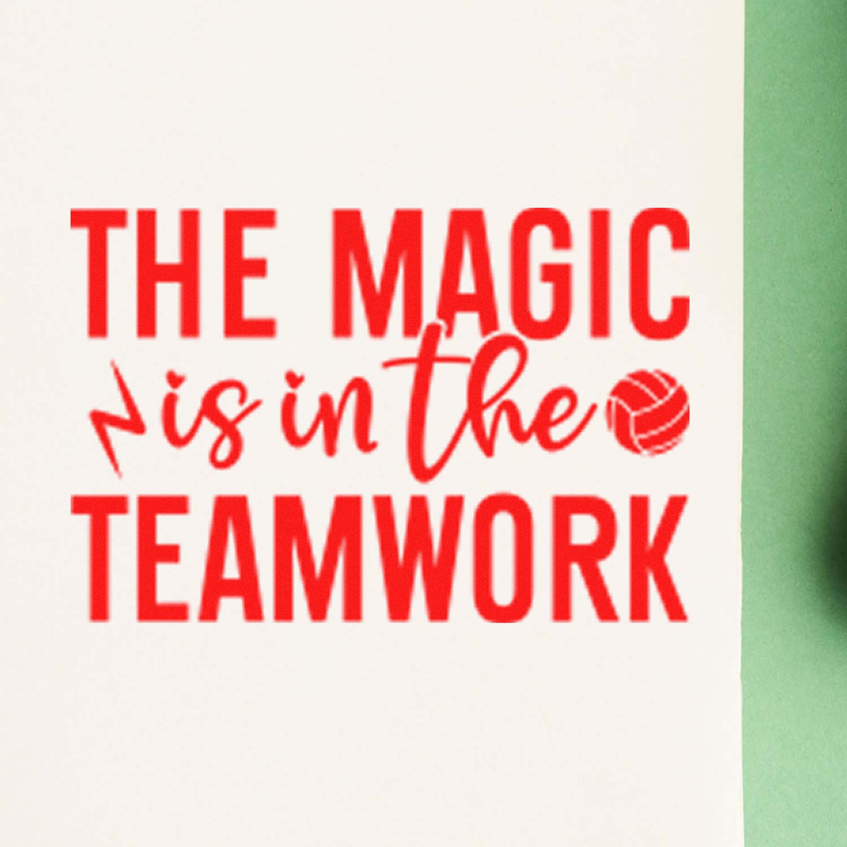 Red rubber stamp seal reading THE MAGIC is in the TEAMWORK in bright red on white, with a green border and volleyball icon.