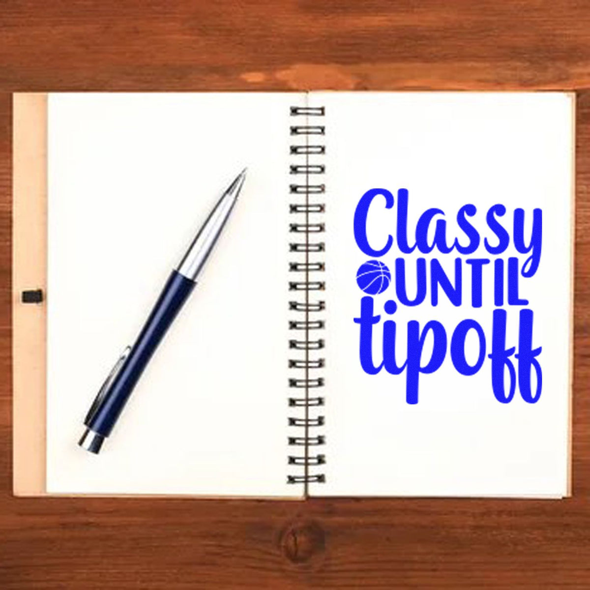 Blue custom stamp seal reading Classy Until Tipoff on a spiral notebook beside a navy pen.