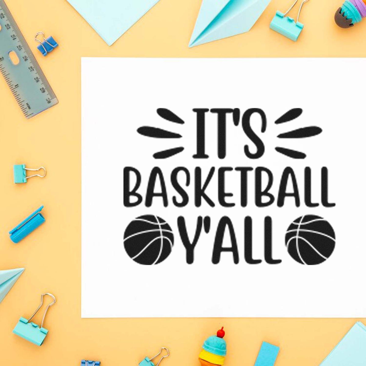 Black basketball-themed stamp design on white paper, reading Its Basketball Yall, with ball icons on a pastel desk.