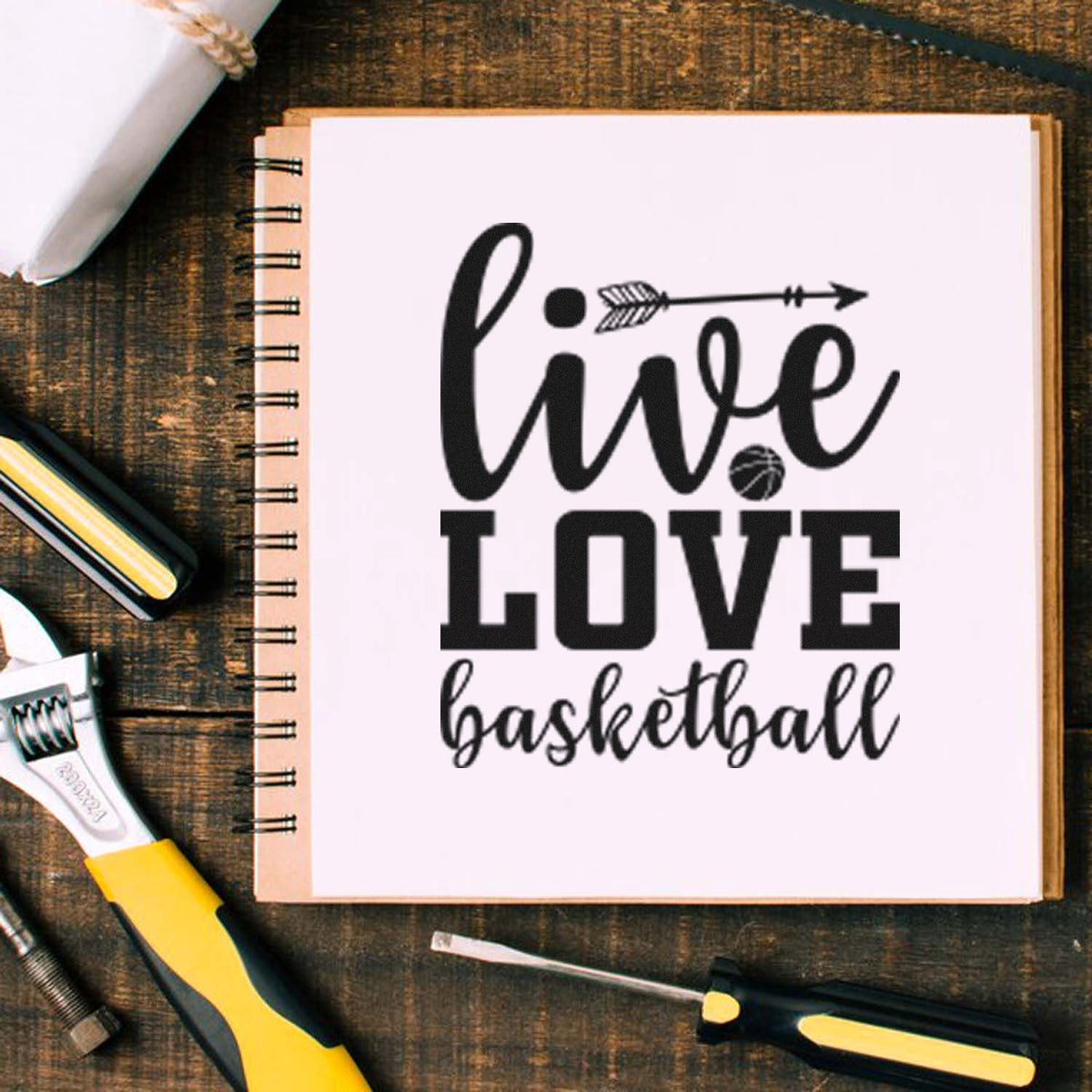 Black basketball stamp and seal on white notebook page, reading live love basketball, with arrow and ball accents.