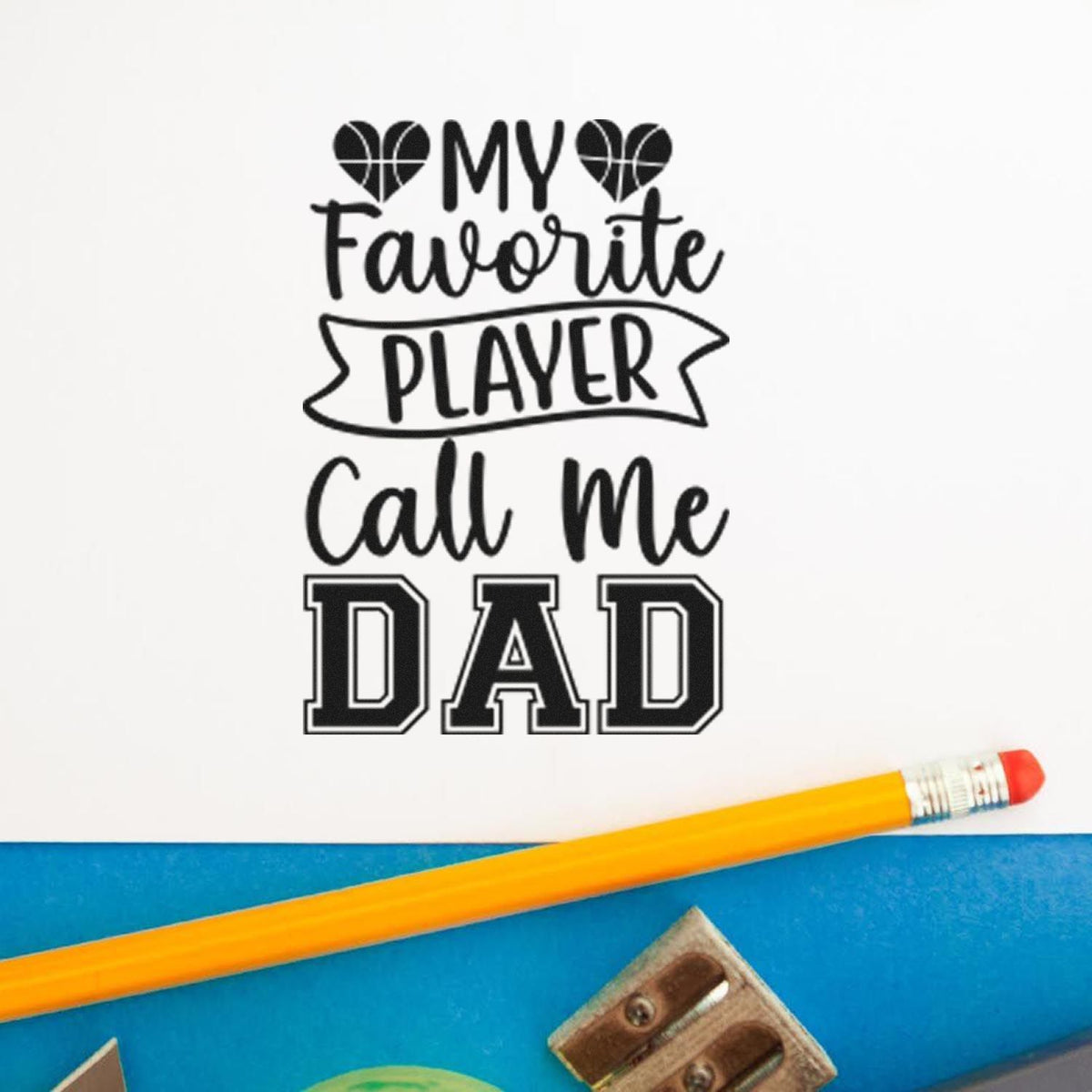 Black custom stamp and seal design reading My Favorite Player Call Me Dad with basketball hearts on white paper beside a yellow pencil.