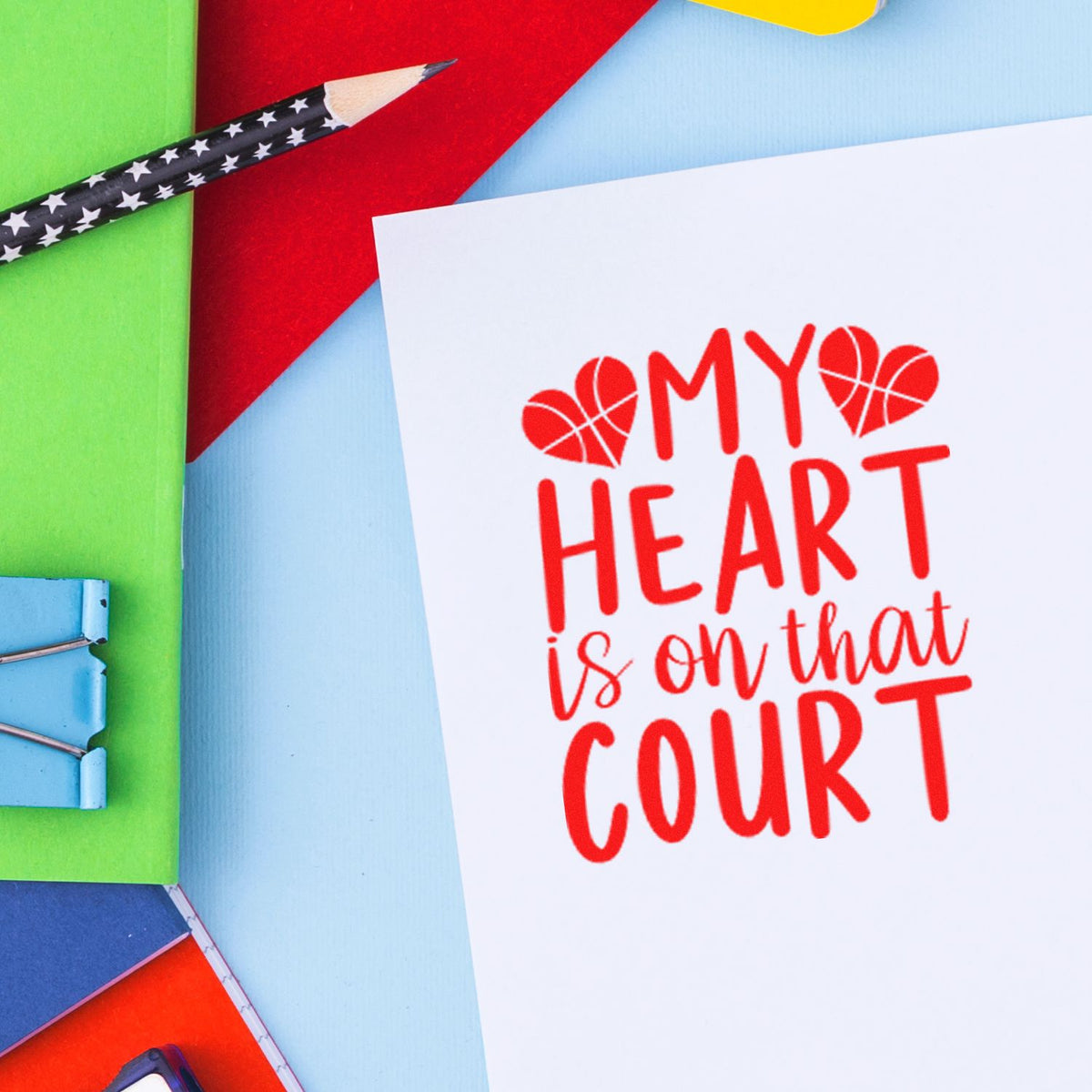 Red heart stamp and seal design on white card reading My heart is on that court, with colorful stationery.