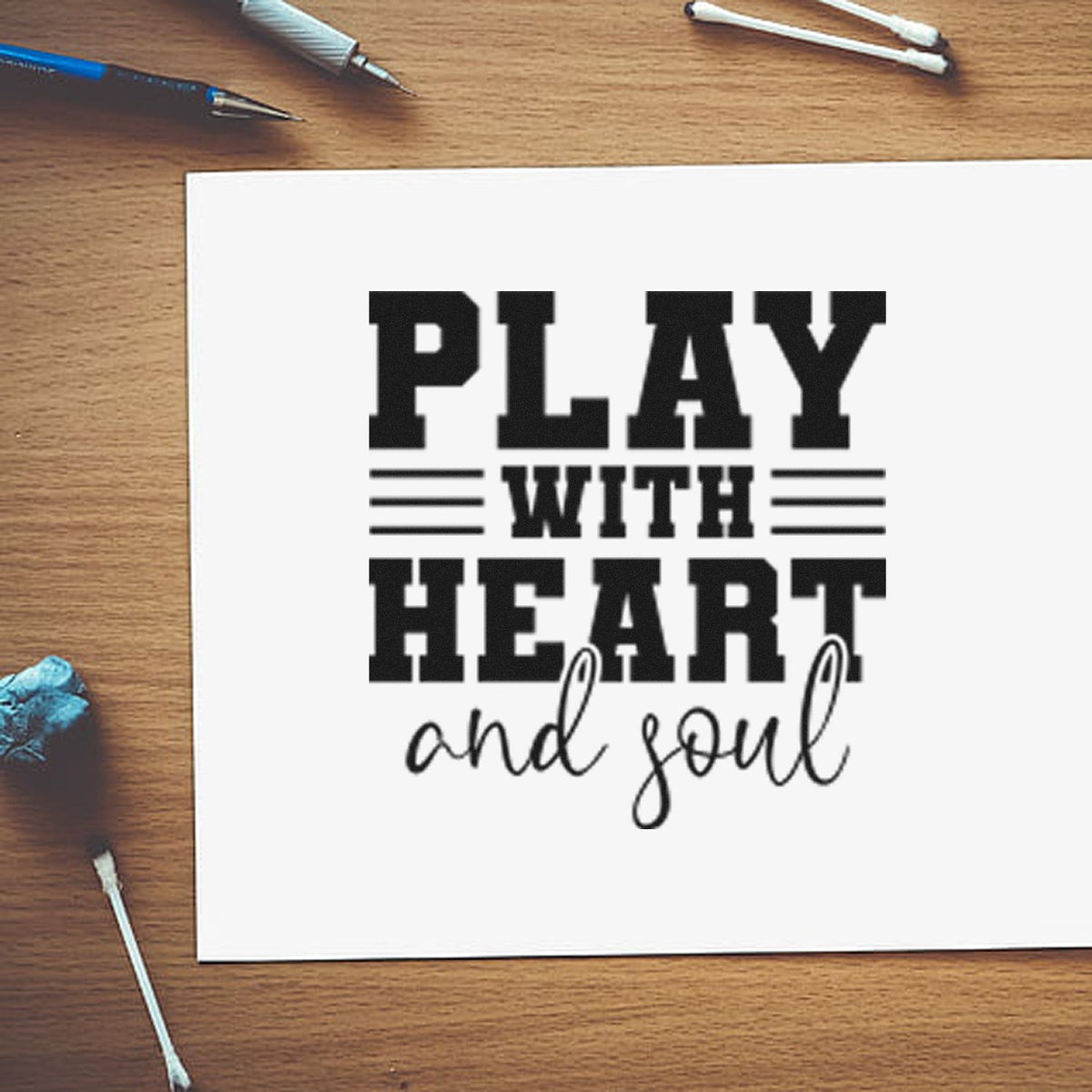 Black custom stamp design reading Play with heart and soul on white paper, with seal tools on a wood desk.