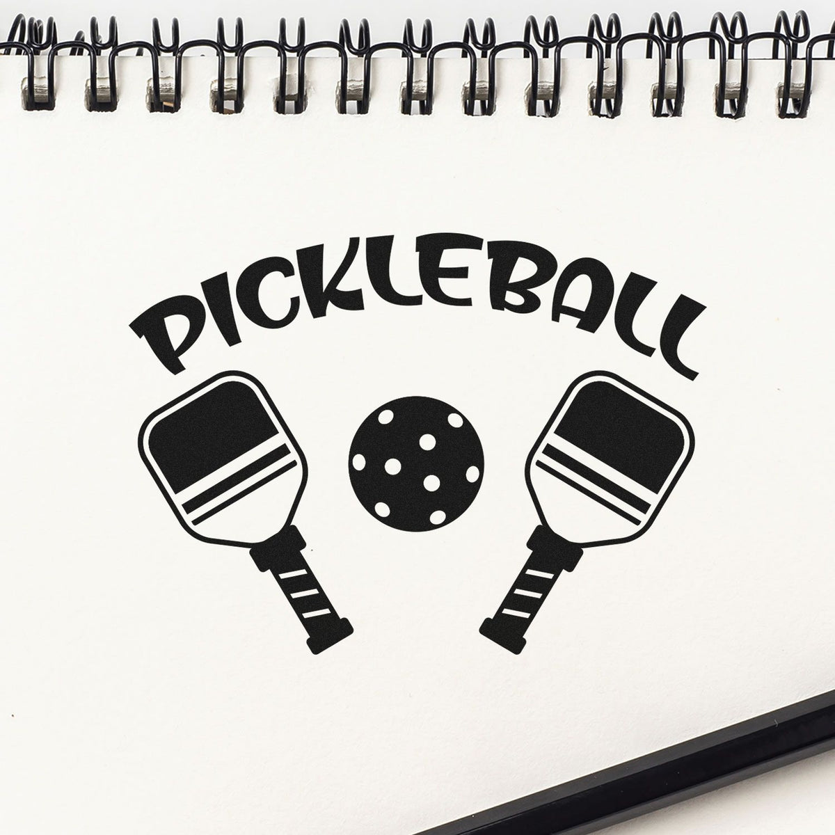Black-and-white pickleball stamp and seal product design with two paddles, dotted ball, and spiral notebook edge.