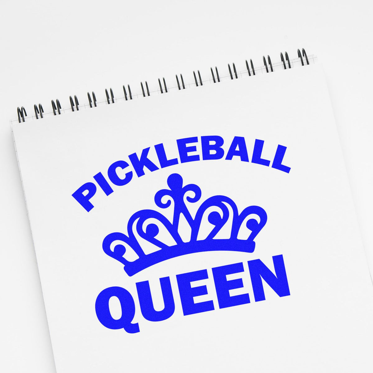 Bold blue Pickleball Queen stamp and seal with crown on a white spiral notepad.