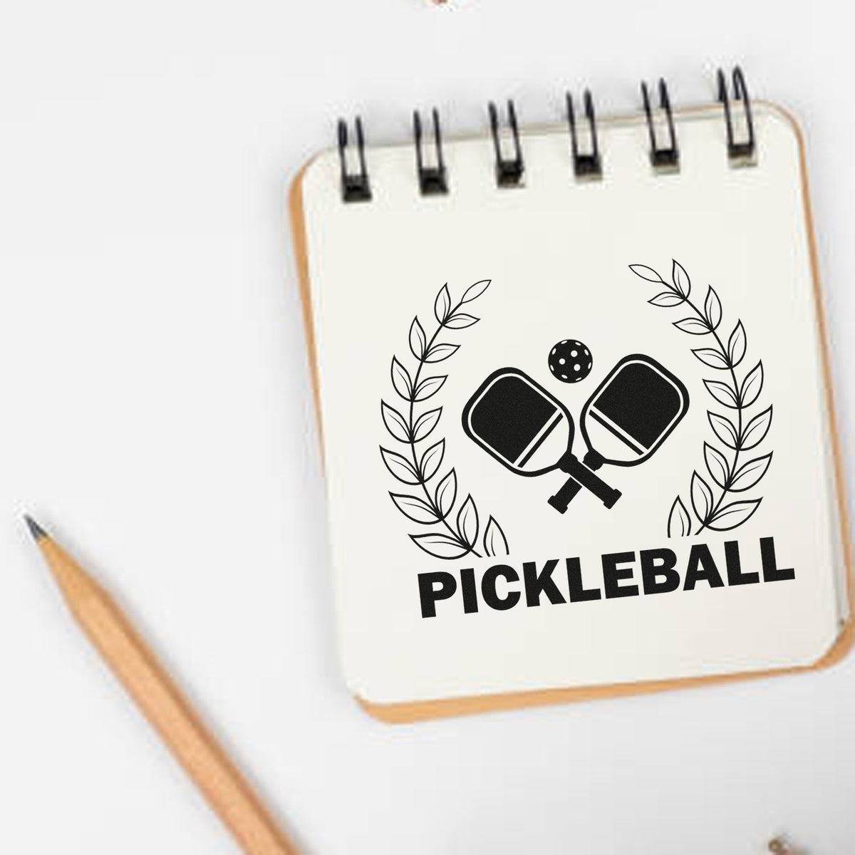 Custom stamp seal design with black pickleball paddles, laurel wreath, and bold PICKLEBALL text on cream background.