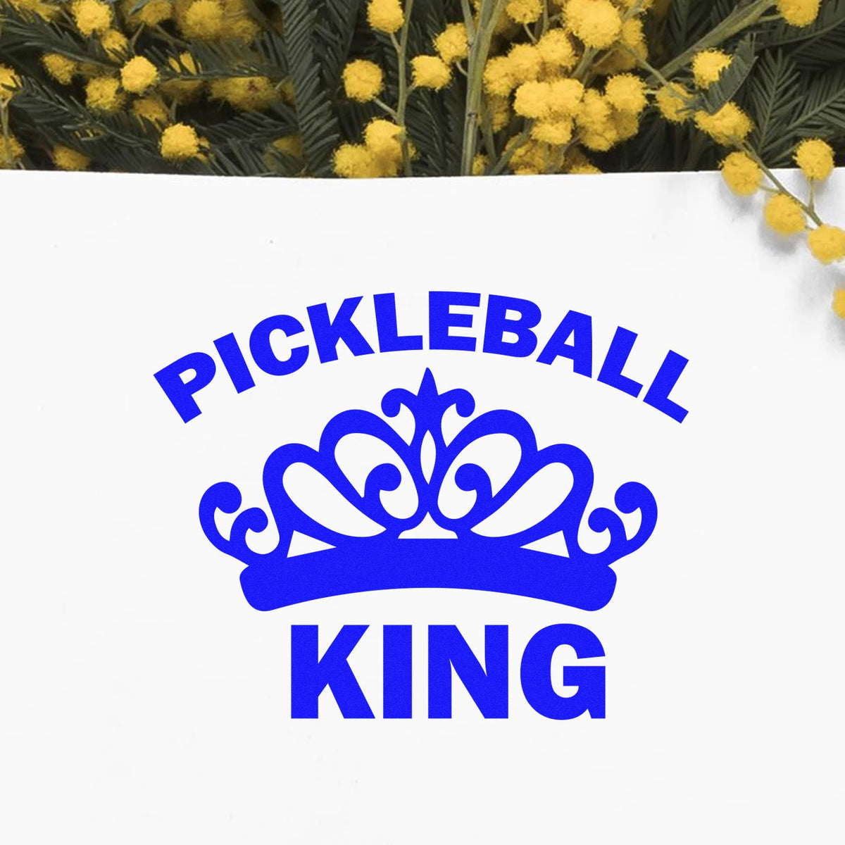 Blue Pickleball King crown stamp and seal on white, with yellow mimosa flowers