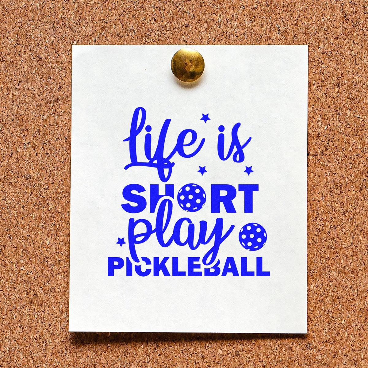 Custom stamp and seal sample on white card, blue life is short play pickleball text, gold brad on cork board.