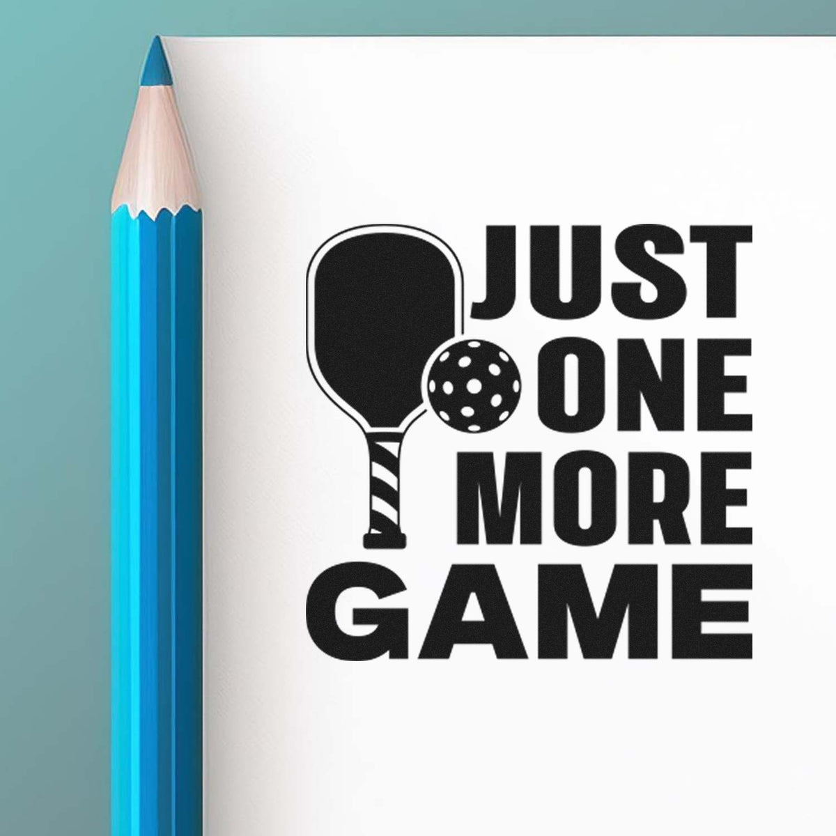 Blue pencil beside black pickleball paddle stamp and seal with ball and Just One More Game text on white.
