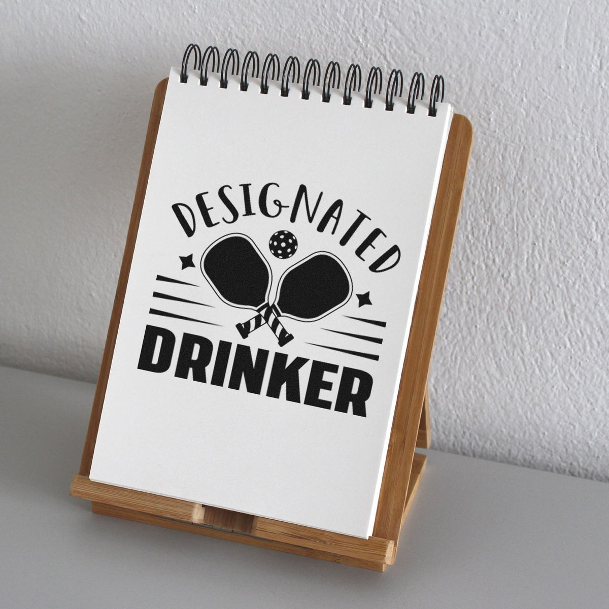 Black Designated Drinker rubber stamp seal on white notepad, with bold black text and two clinking glasses graphic.