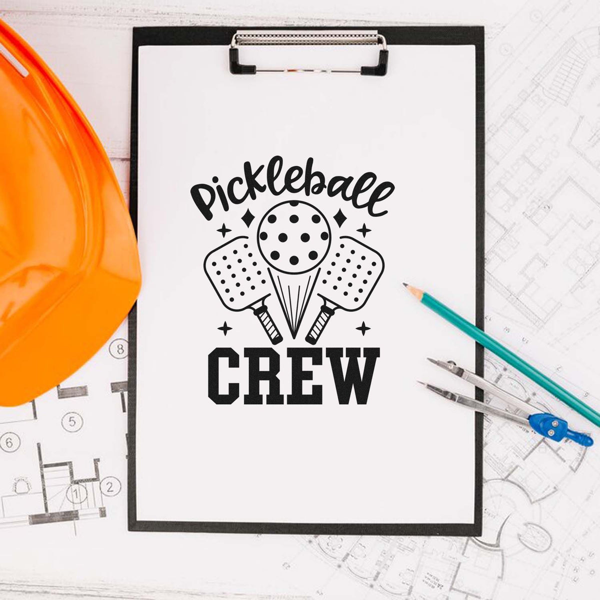 Black pickleball crew stamp design on clipboard, with paddles, ball, orange hard hat, teal pencils, and blueprints.