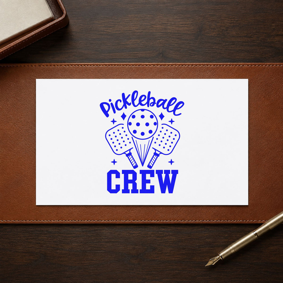 Pickleball Crew Paddles Ball craft stamp imprinted in blue ink on paper, a design suited to framed court bench.