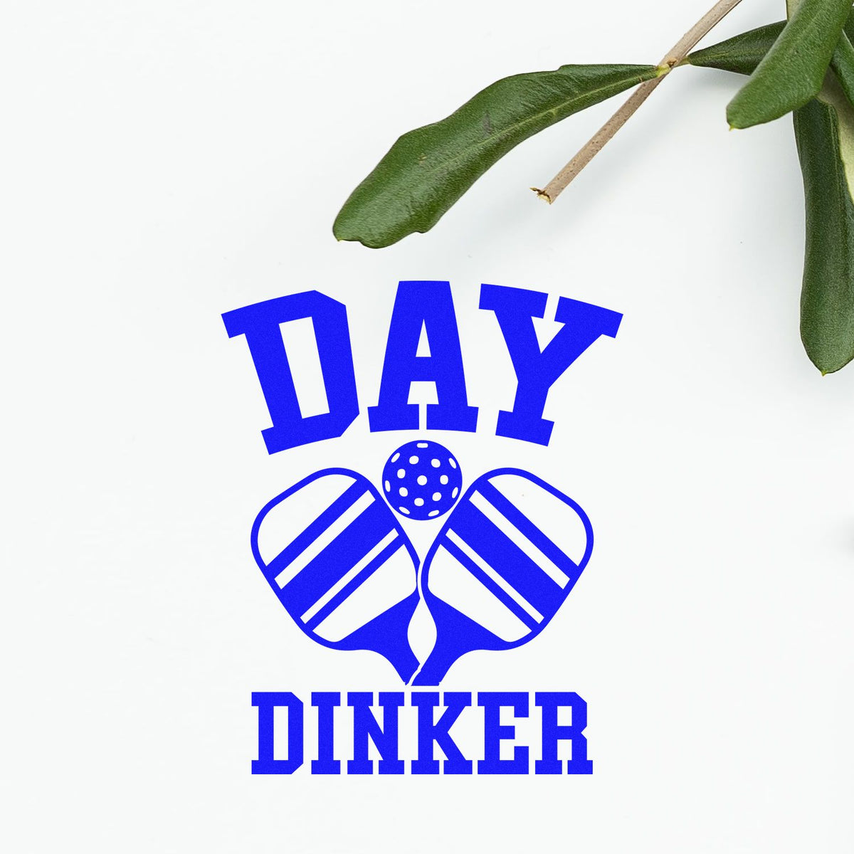 Blue Day Dinker stamp and seal design with pickleball paddles and ball, set on a white background with green leaves.