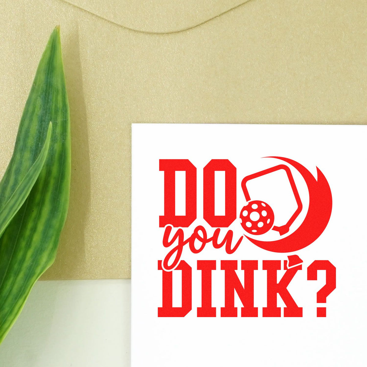 Red DINK? pickleball stamp and seal design on white card, bold red lettering and ball icon, beside a green leaf.