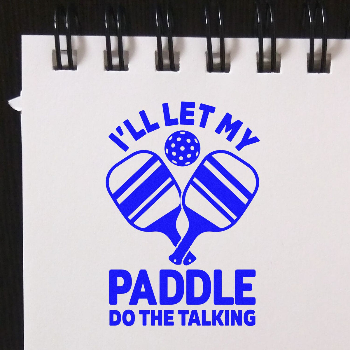 Blue custom stamp seal with crossed padel paddles and ball, reading ILL LET MY PADDLE DO THE TALKING on white background.