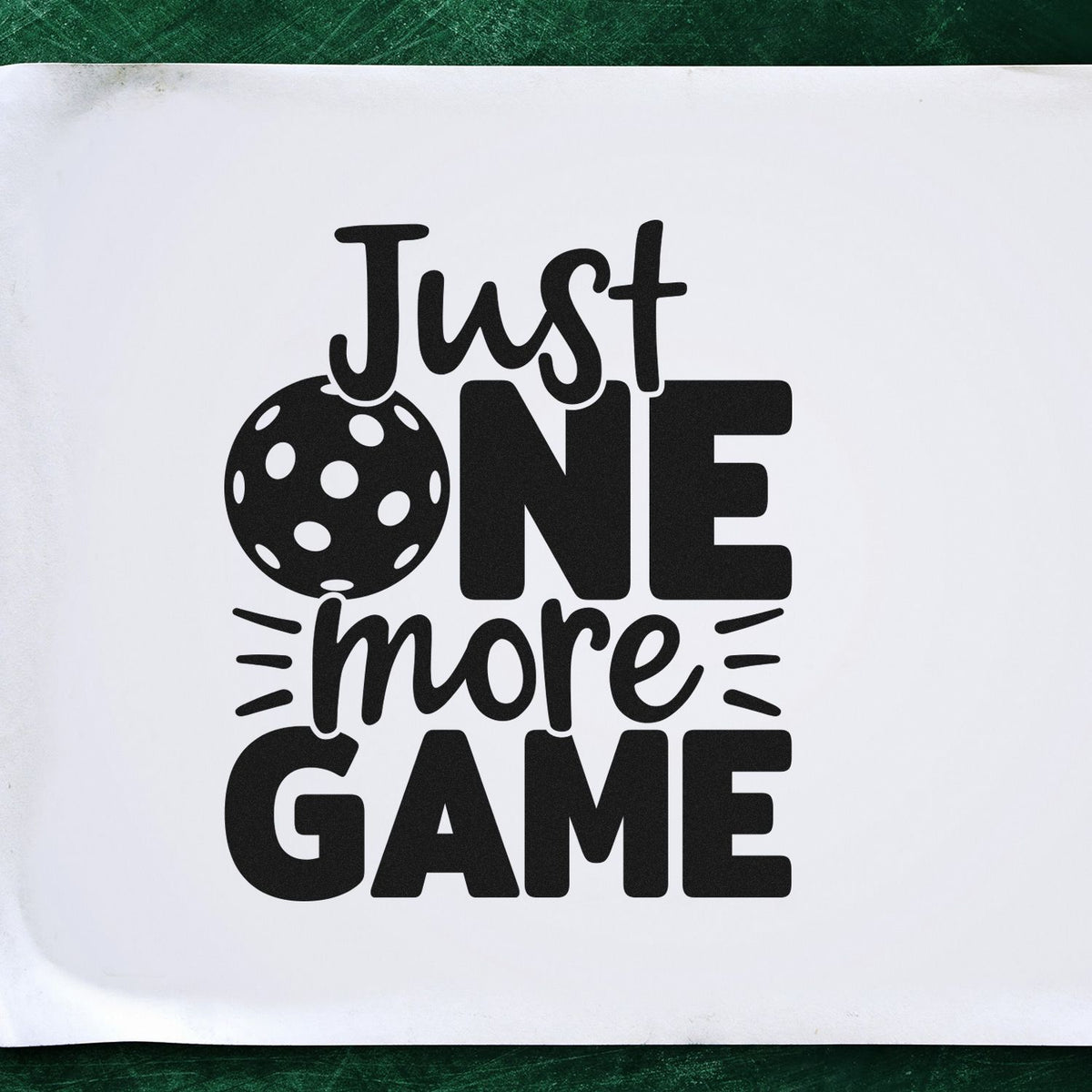 Black Just One More Game stamp and seal design with a polka-dot ball on white, framed by dark green.