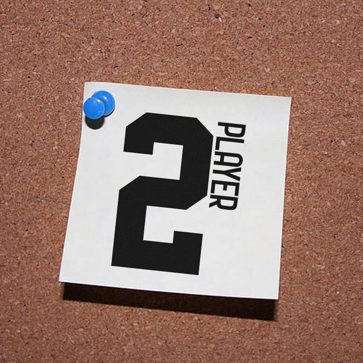 Custom stamp and seal card with bold black 2 and PLAYER text, pinned with a blue pushpin on corkboard.