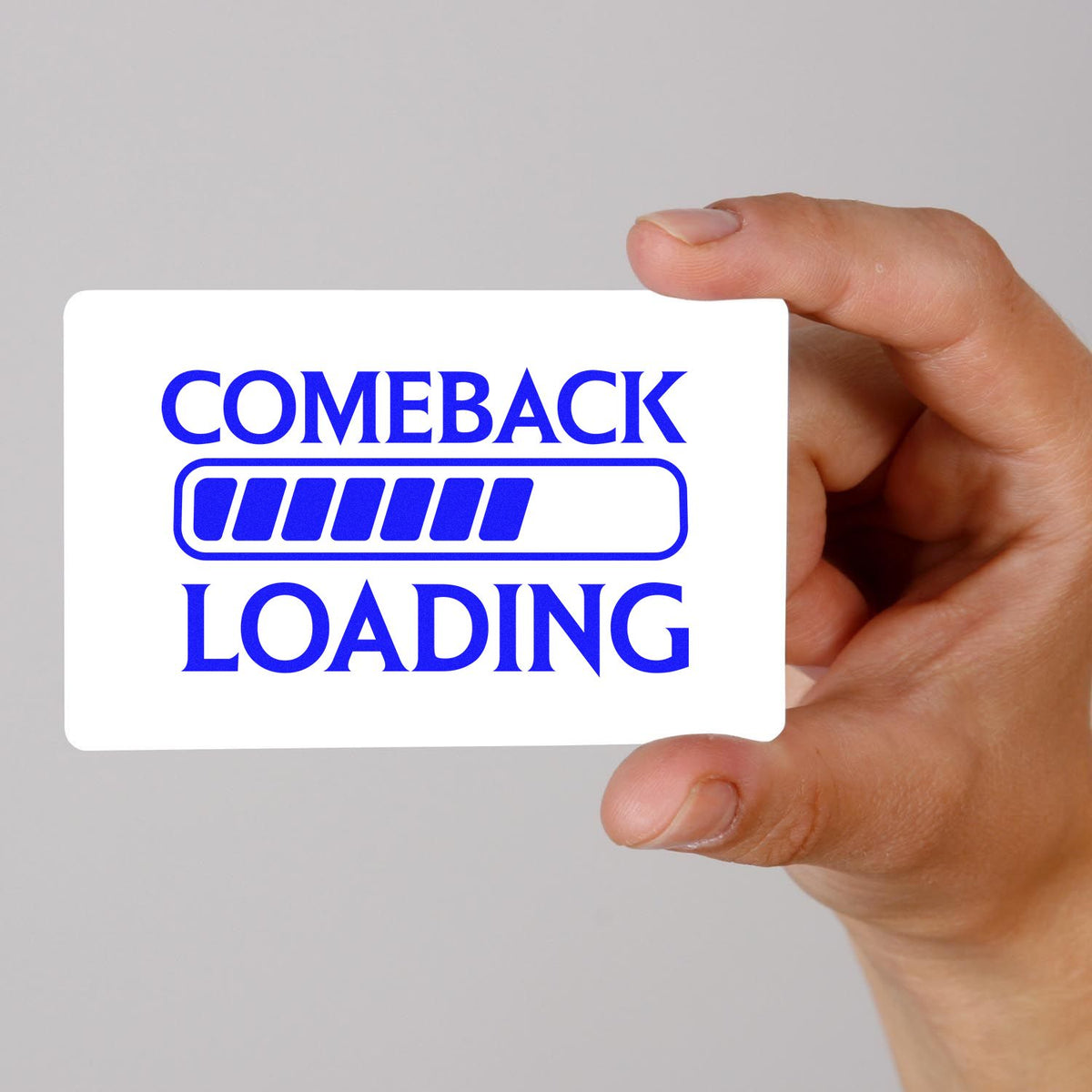 Hand holding white rubber stamp seal card with blue COME BACK LOADING text and progress bar