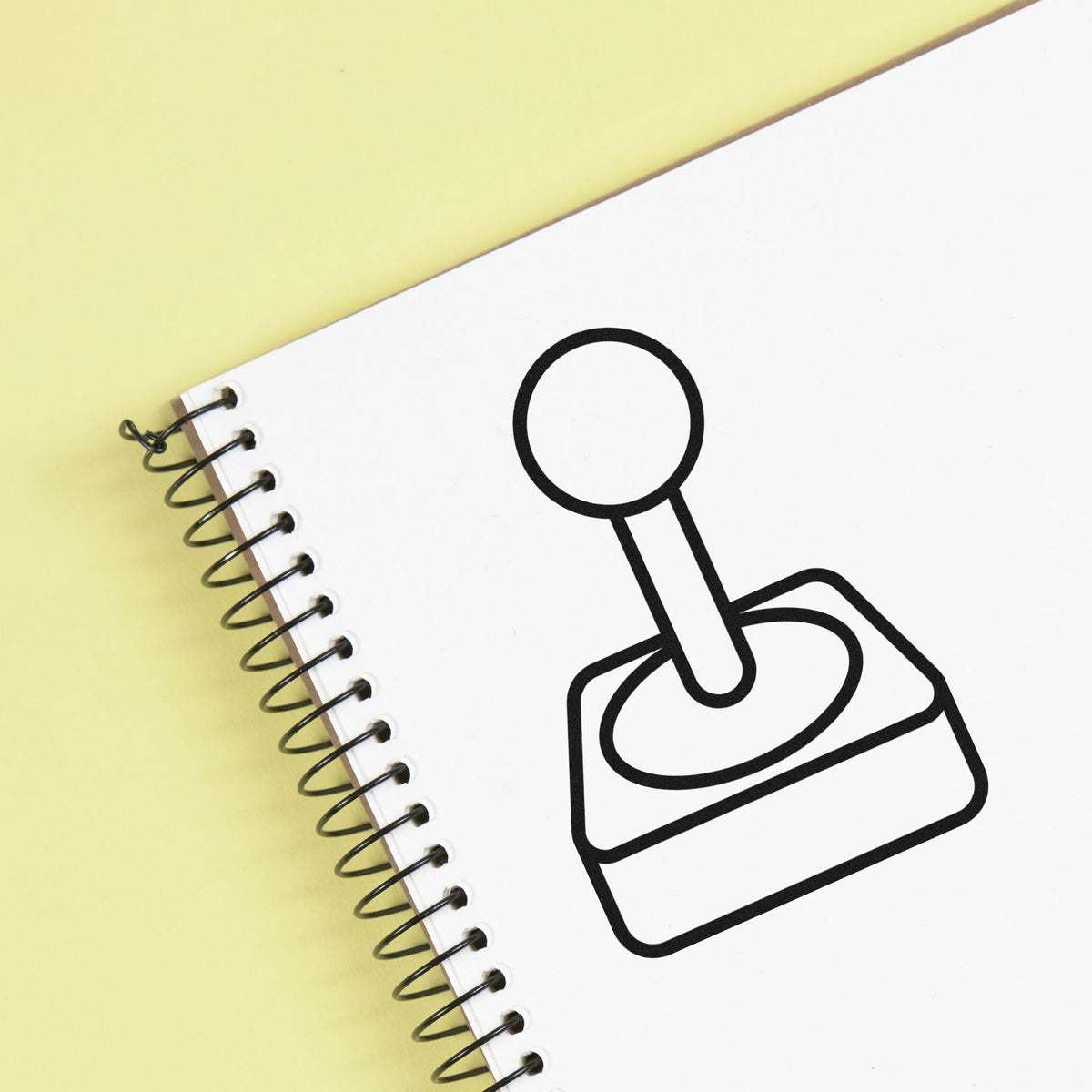 Black rubber stamp icon on a white spiral notebook against a pale yellow background, representing stamp and seal products.