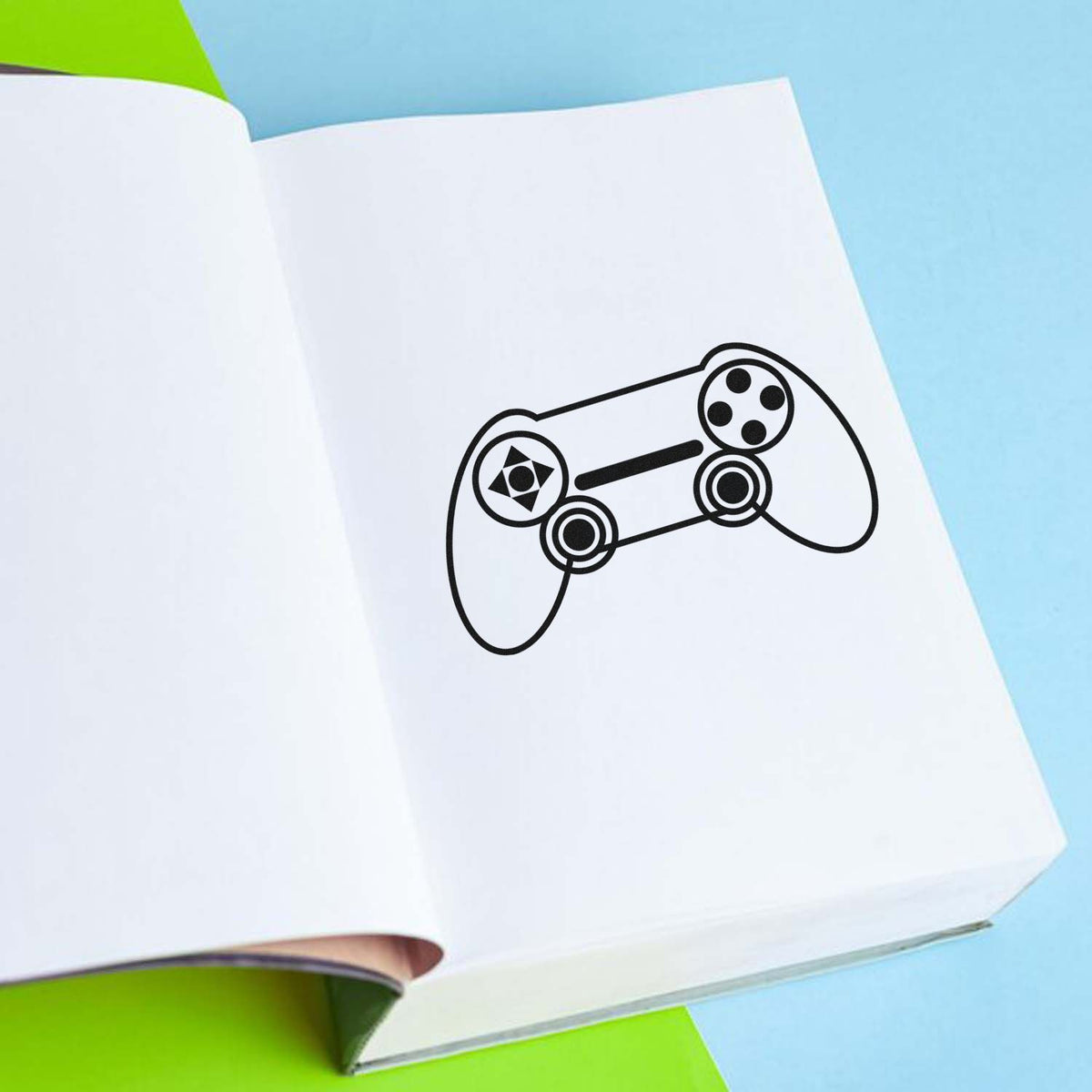 Black game controller stamp and seal on white paper, with blue and green background.