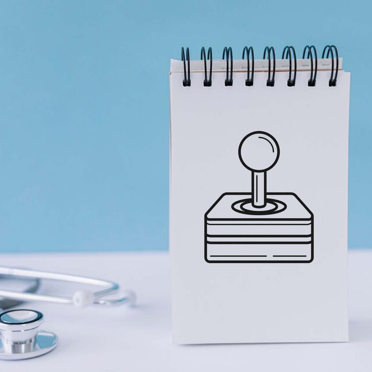 White spiral notepad with black stamp-and-seal icon on a blue background, with a stethoscope in the foreground.