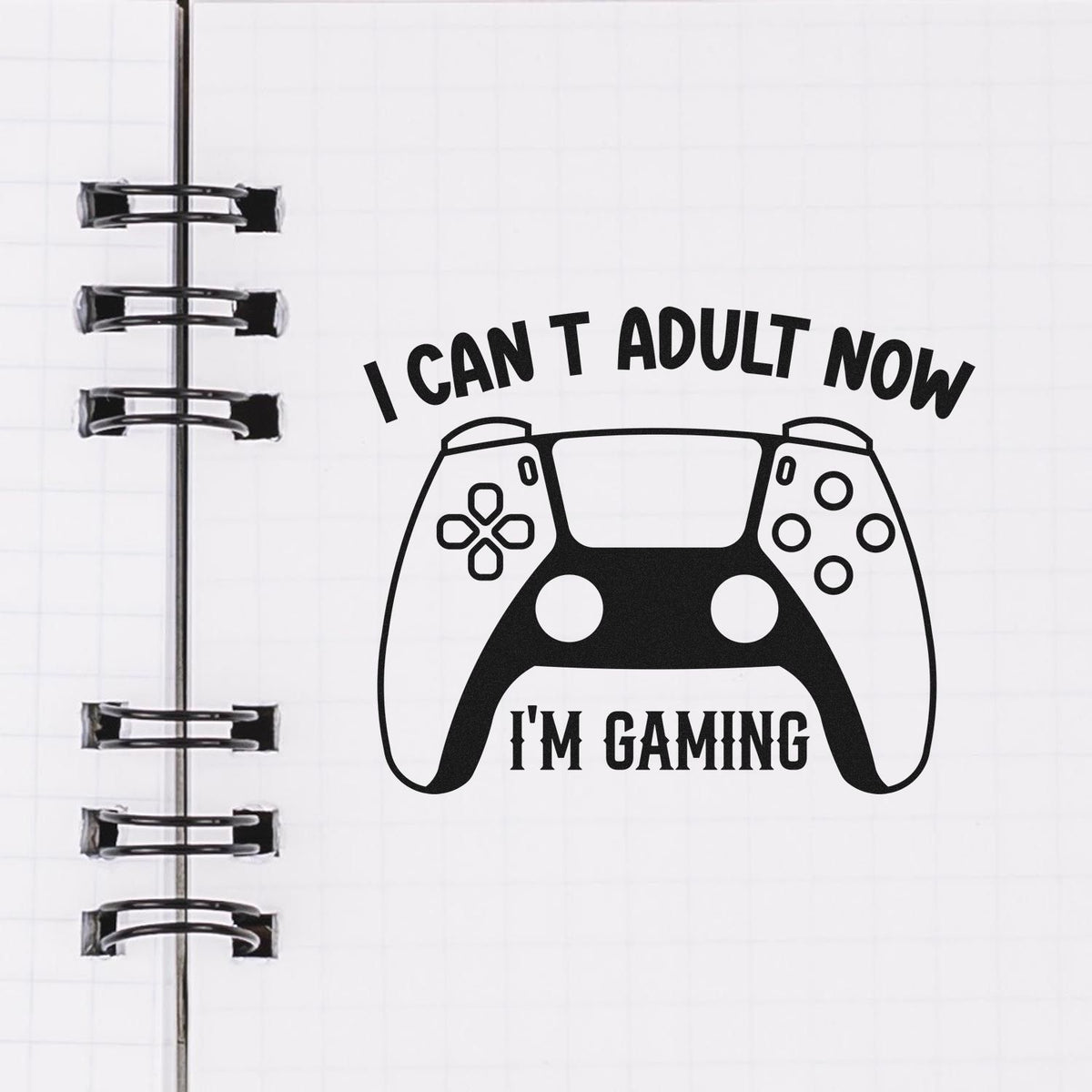 Black stamp and seal design with a gaming controller and bold text I CANT ADULT NOW IM GAMING on white notebook paper.