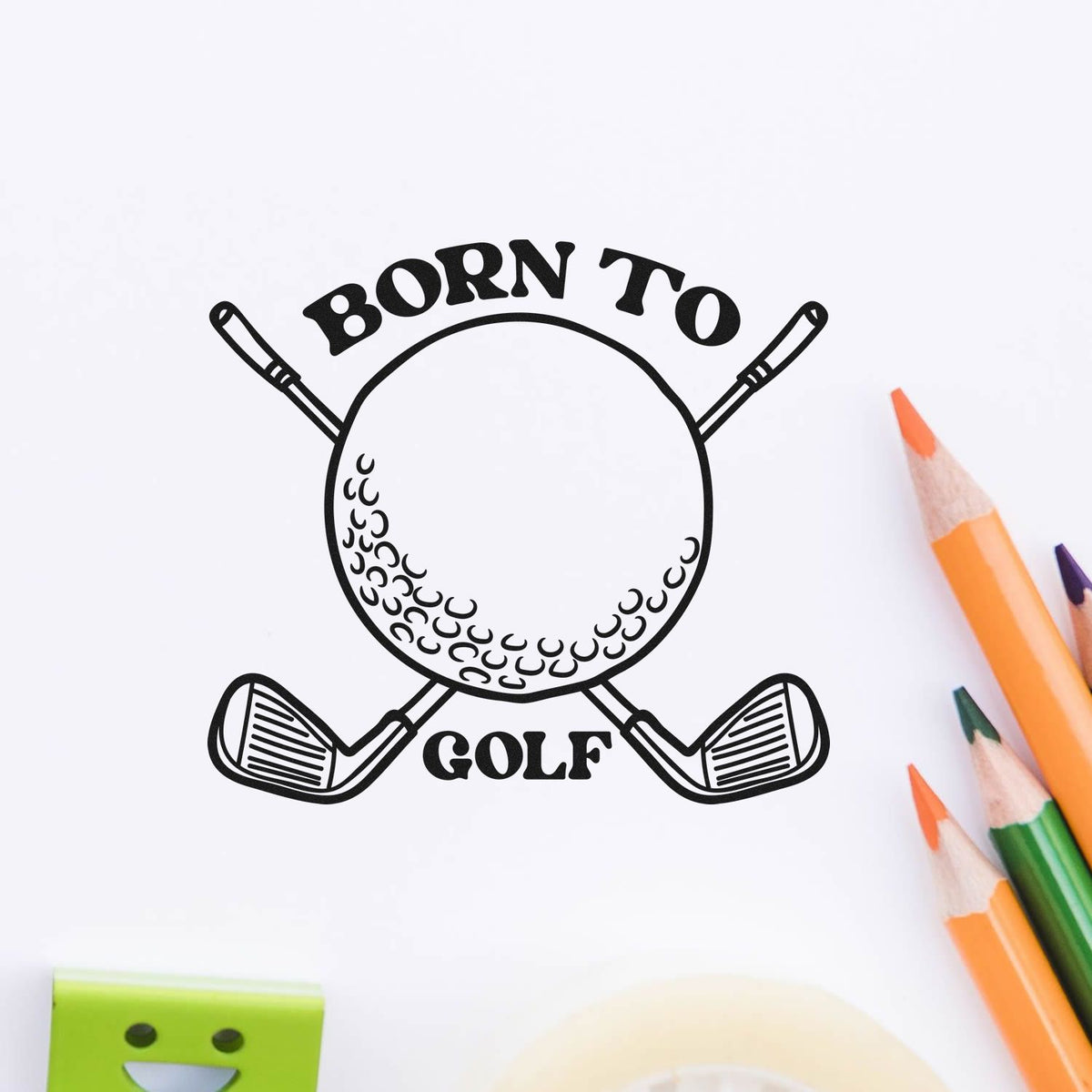 Black Born to Golf stamp seal with crossed clubs and golf ball, on white paper beside orange and green pencils.