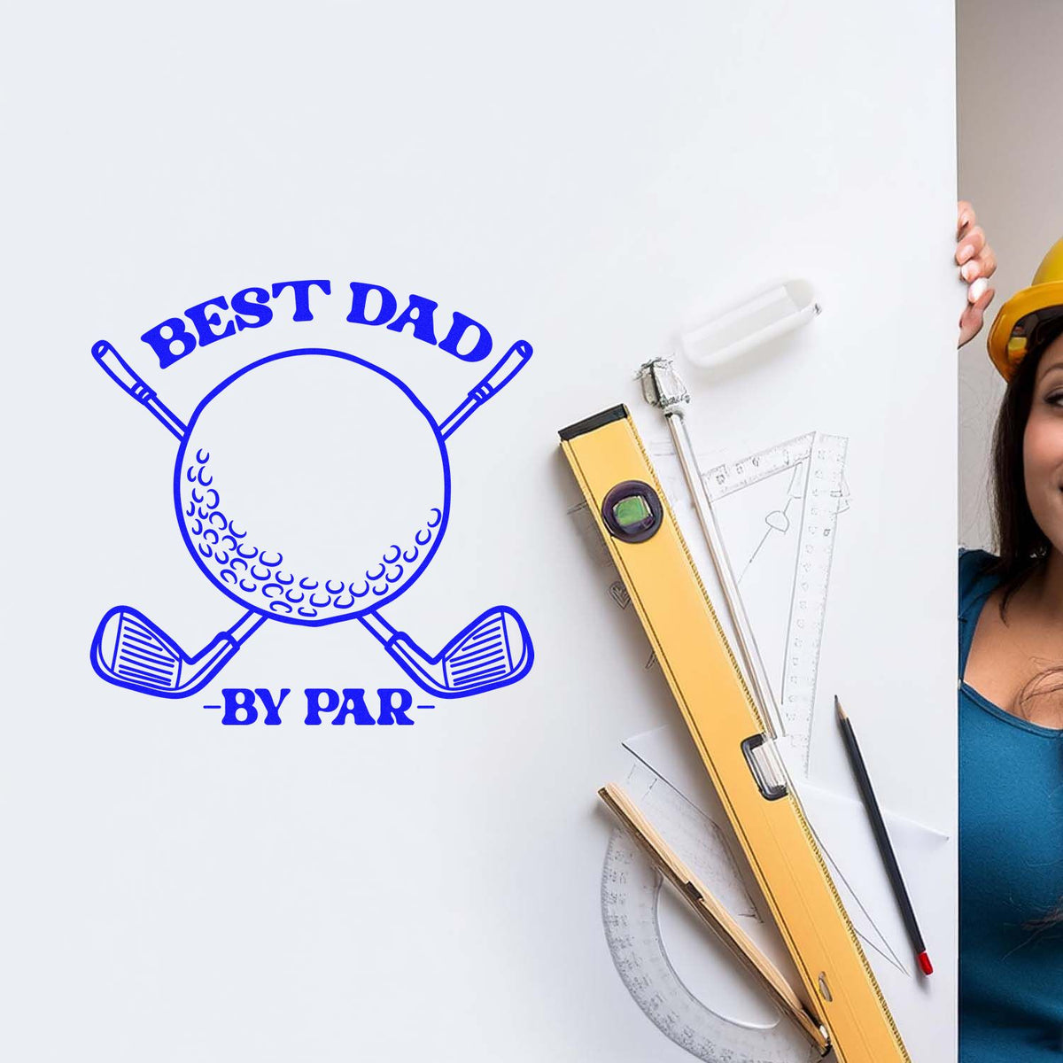 Blue custom stamp and seal reading Best Dad with golf clubs, beside drafting tools and a yellow level on a white board.