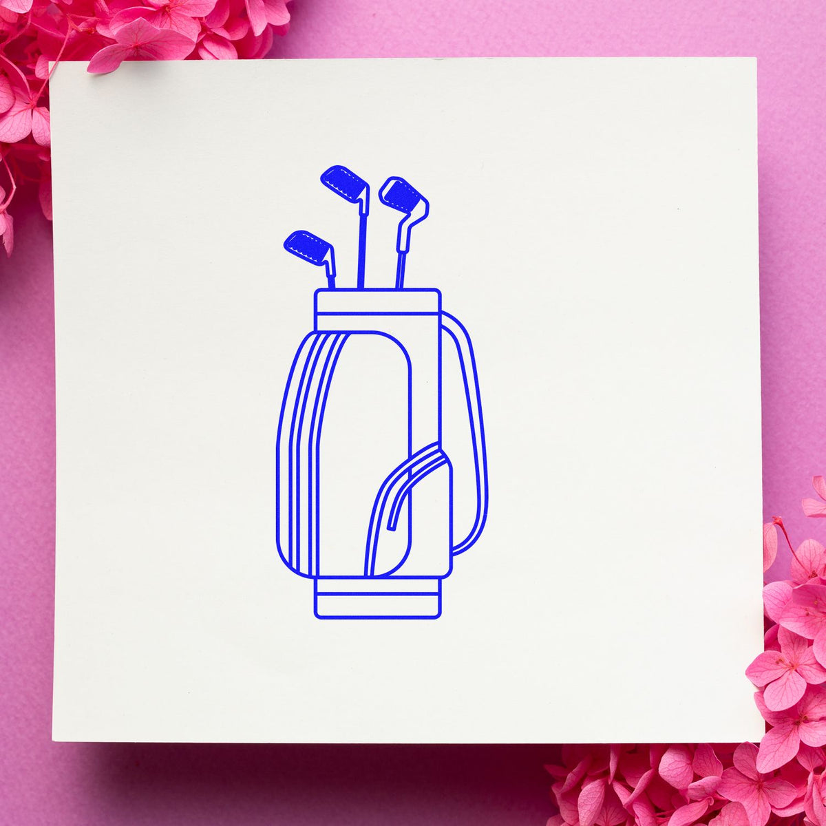 Blue golf bag stamp seal on a white square card, framed by bright pink flowers.