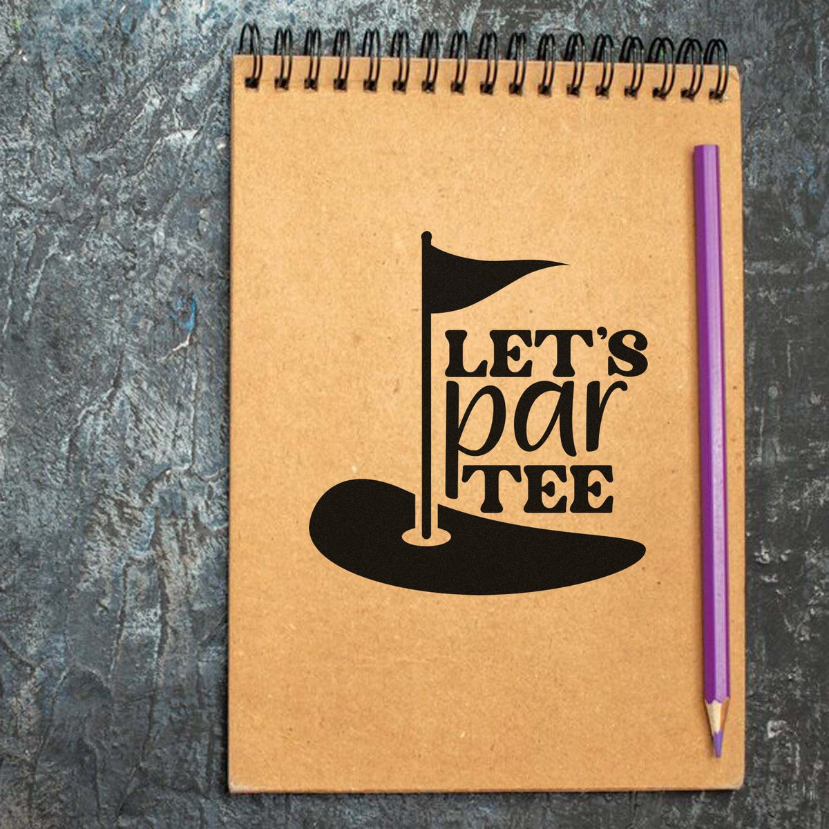 Custom golf stamp seal design on kraft spiral notebook, black Lets par tee flag logo, purple pencil.