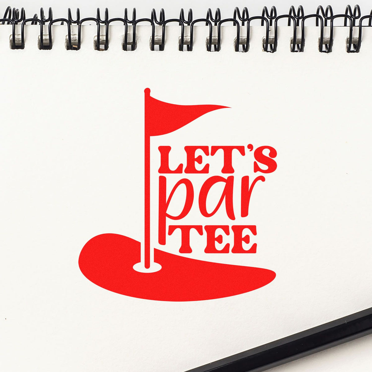 Red golf-themed stamp and seal product with a flag and LETS par TEE on a white spiral notebook