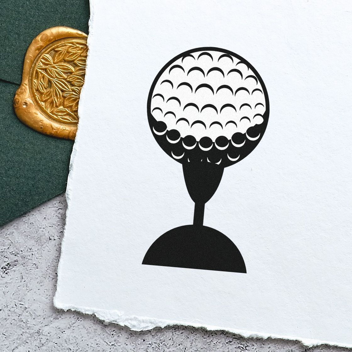 Black golf-ball stamp on white paper beside a gold embossed seal on dark green felt.