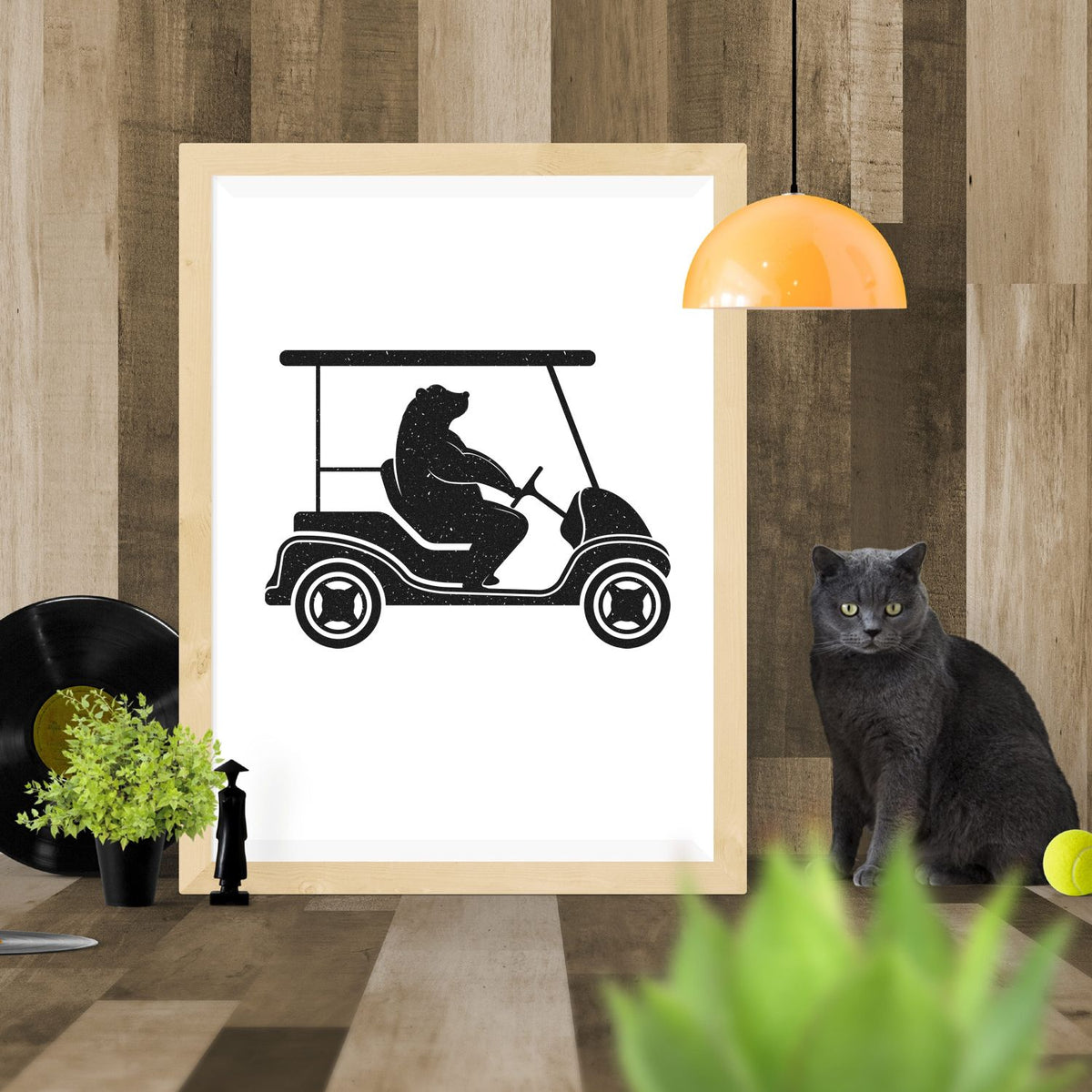 Black golf cart stamp and seal design featuring a bear silhouette on a white framed print, with wood frame and orange lamp.
