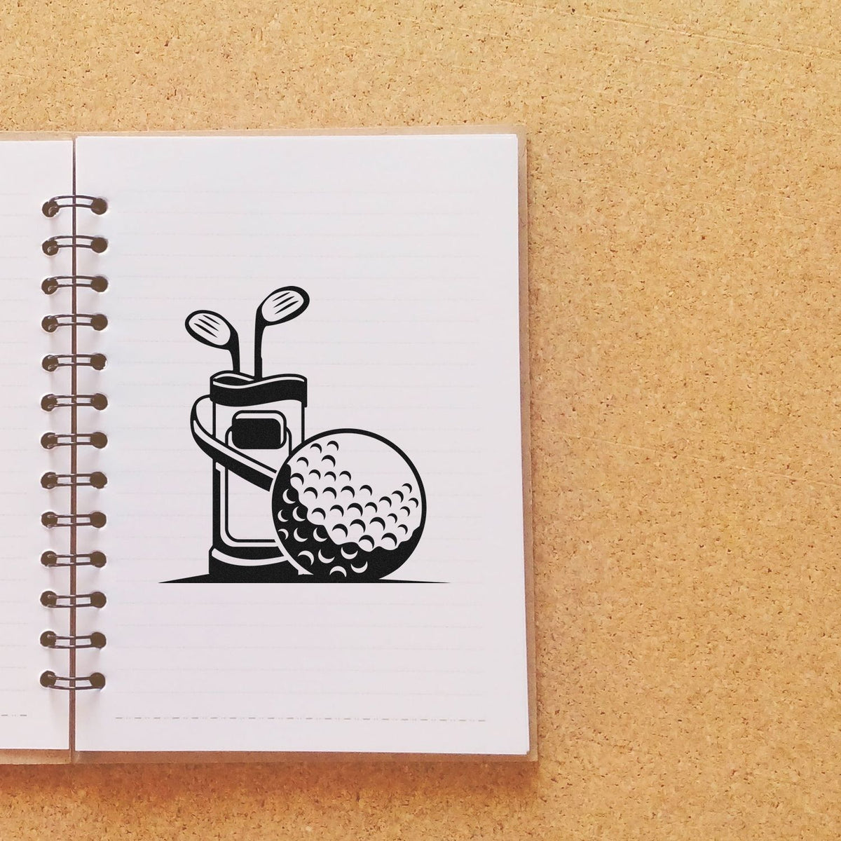 Black golf club stamp and seal on white spiral notebook against tan cork background.