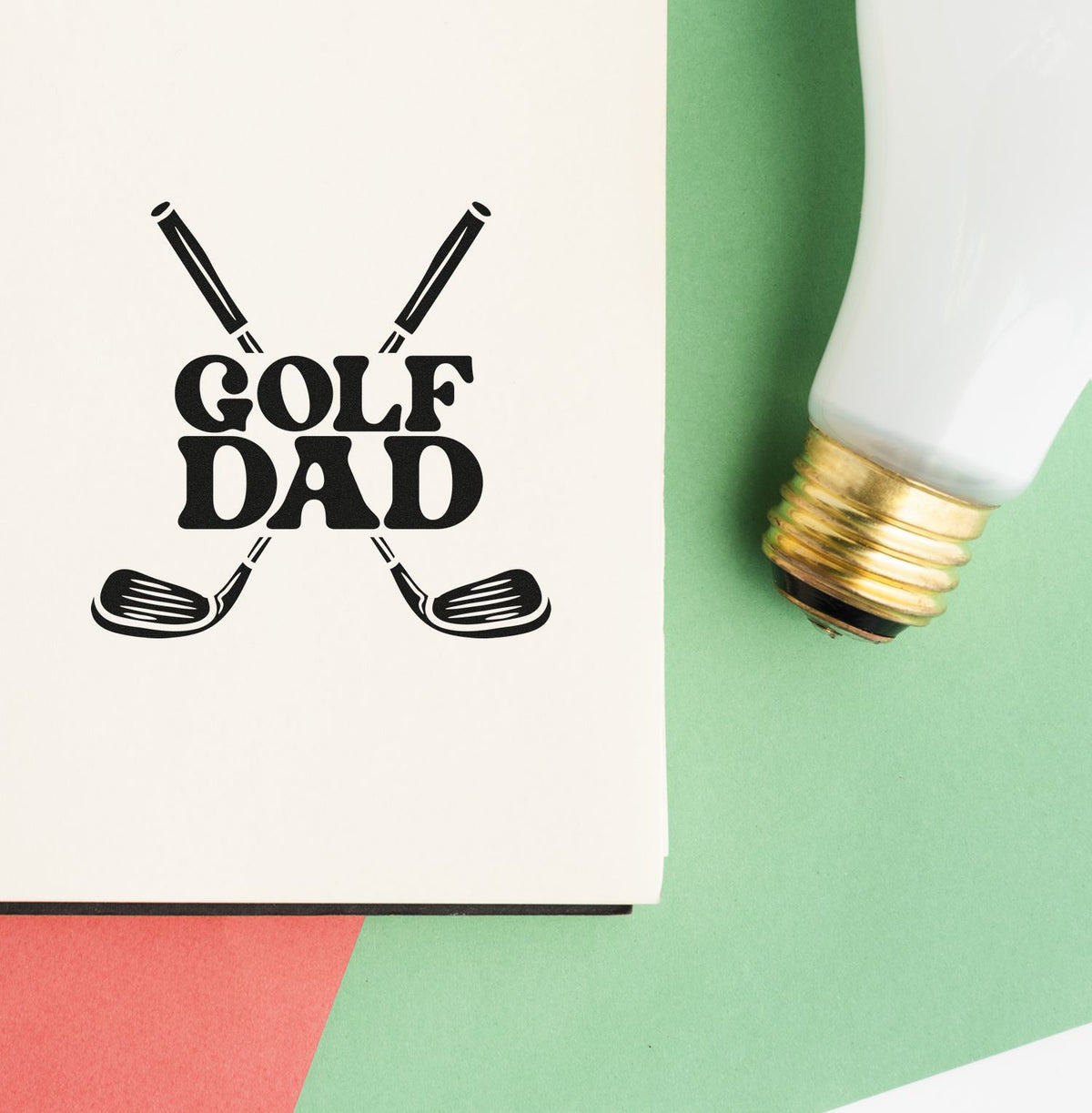 Golf Dad stamp and seal design with crossed clubs, white-and-gold tool, on green and coral background.
