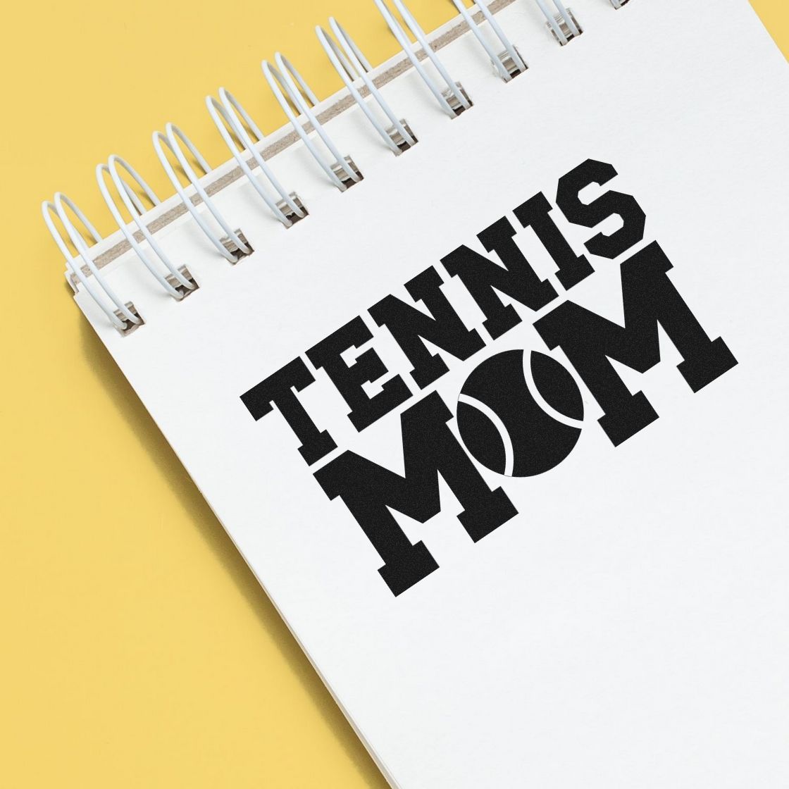 Tennis Mom rubber stamp and seal design on white spiral notebook with black lettering and tennis ball graphic on yellow background