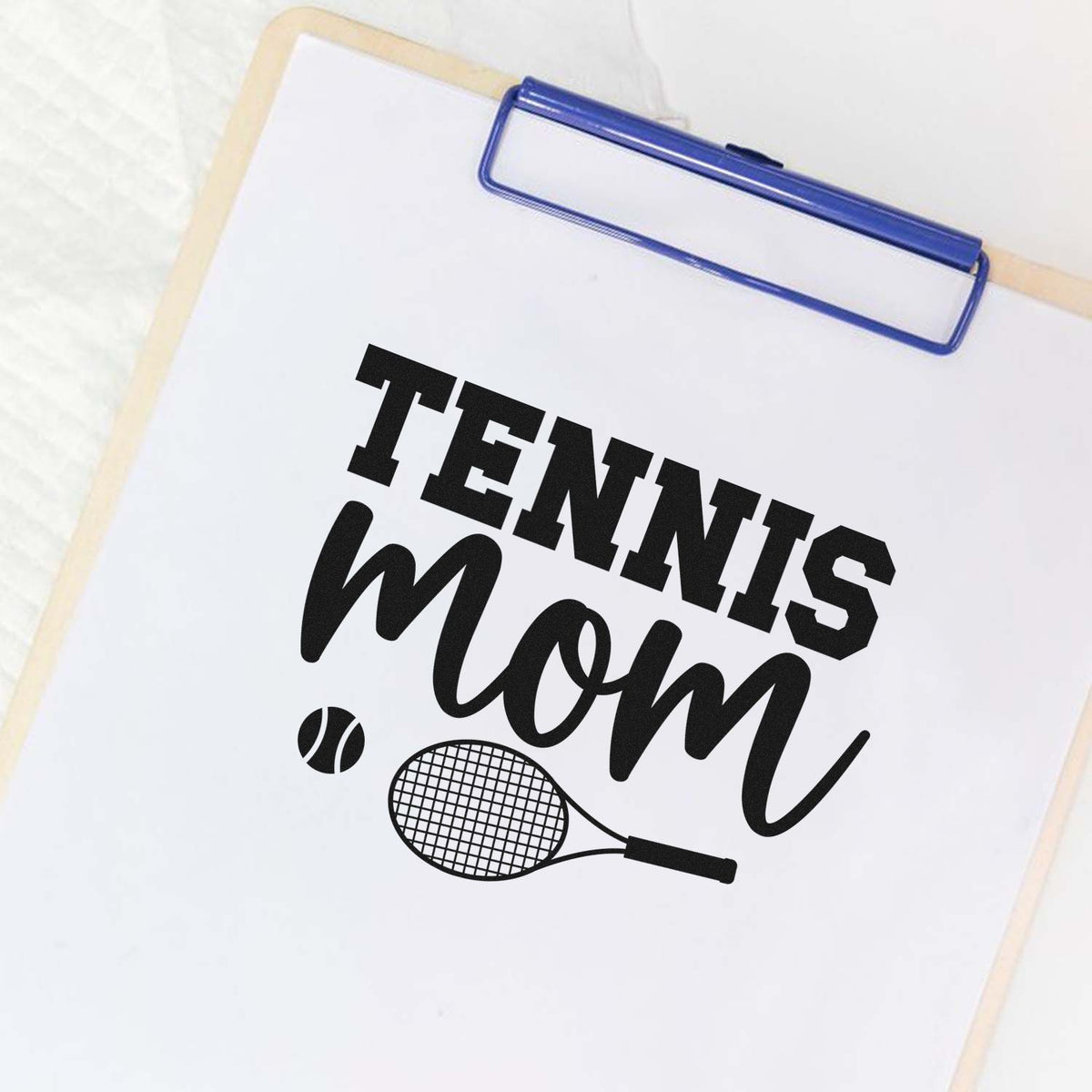 Blue clipboard stamp and seal product featuring black Tennis Mom text, tennis ball and racket on white paper