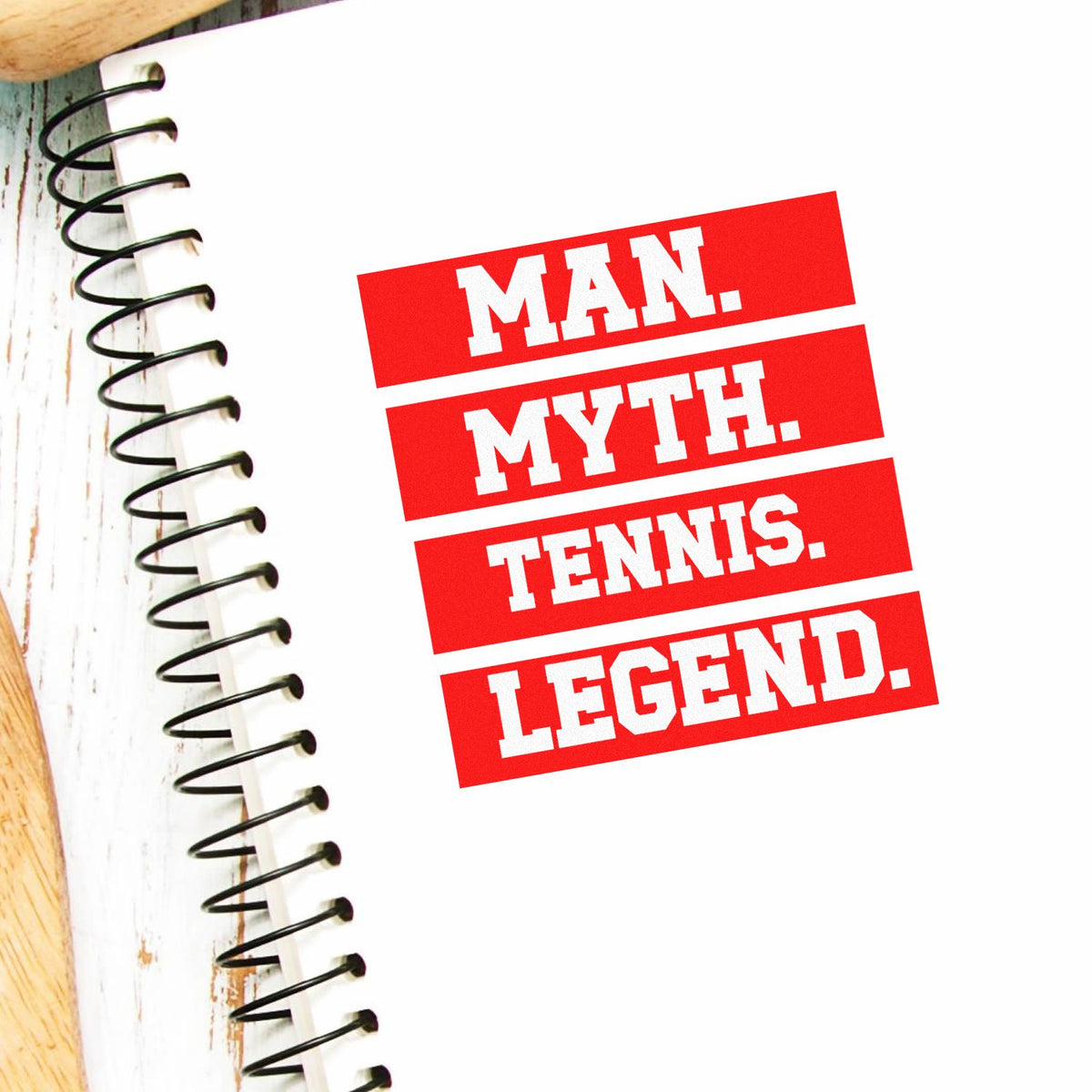 Red and white stamp-style seal reading MAN. MYTH. TENNIS. LEGEND. beside a spiral notebook.