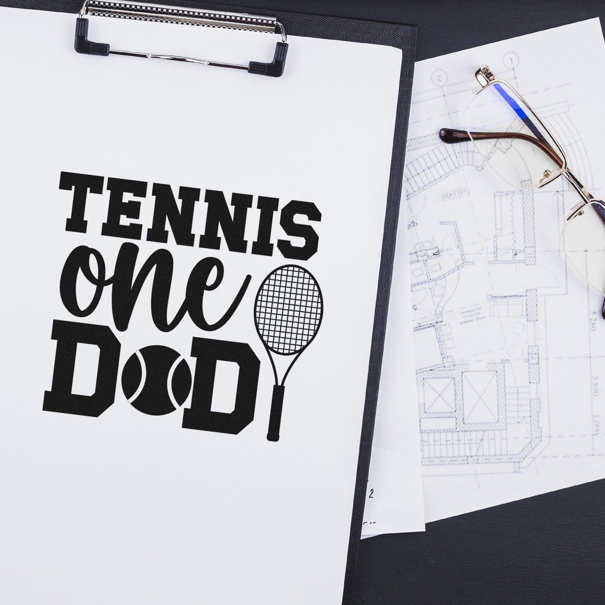 Black tennis-themed stamp and seal design on white clipboard, with tennis racket graphic and blueprint sketches beside eyeglasses.