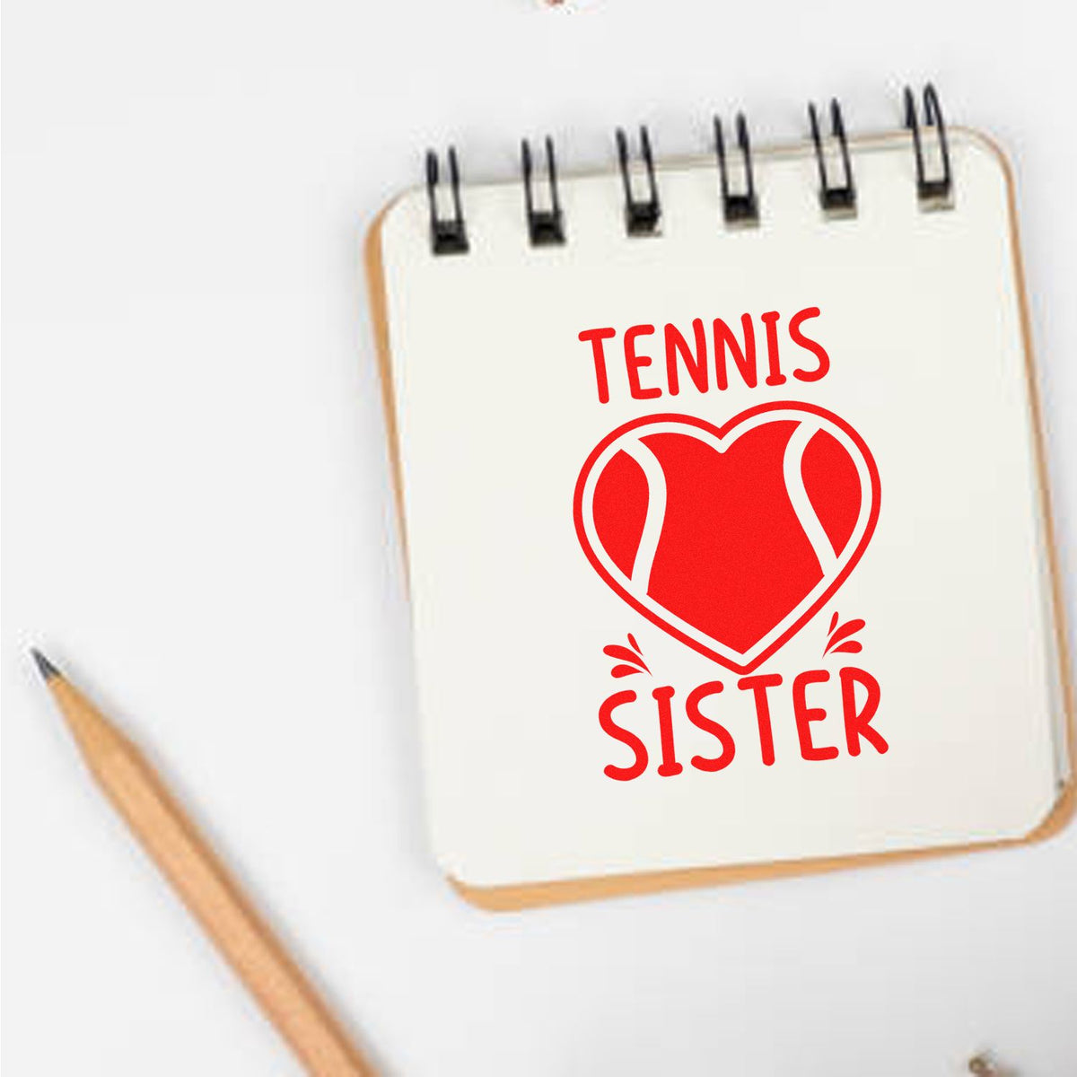 Red tennis sister stamp seal design on a white notebook, with heart-shaped tennis ball graphic and pencil.