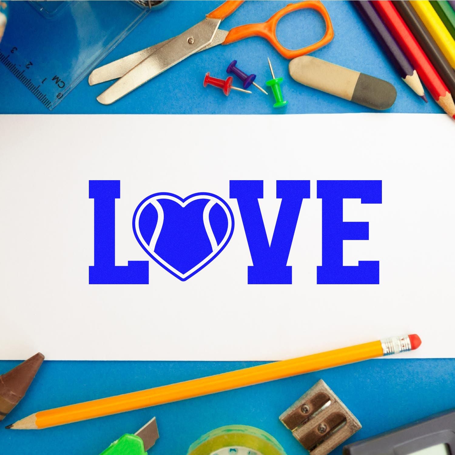 Blue LOVE stamp with heart seal on white paper, surrounded by colorful stationery on a blue background.