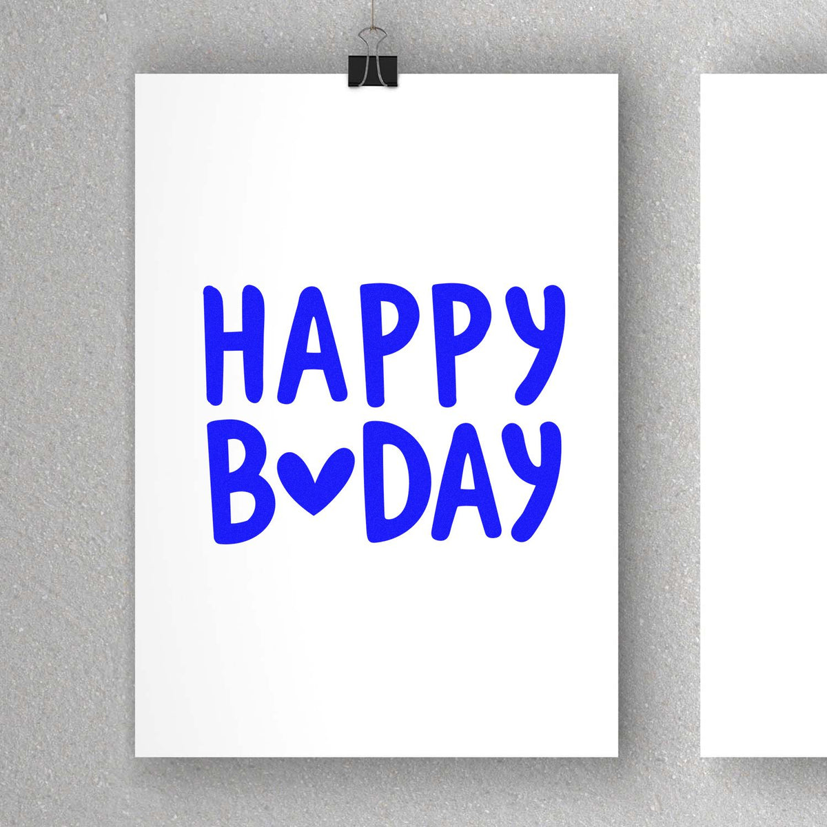 Blue HAPPY B?DAY stamp seal on white card, clipped with a black binder clip on a gray background.