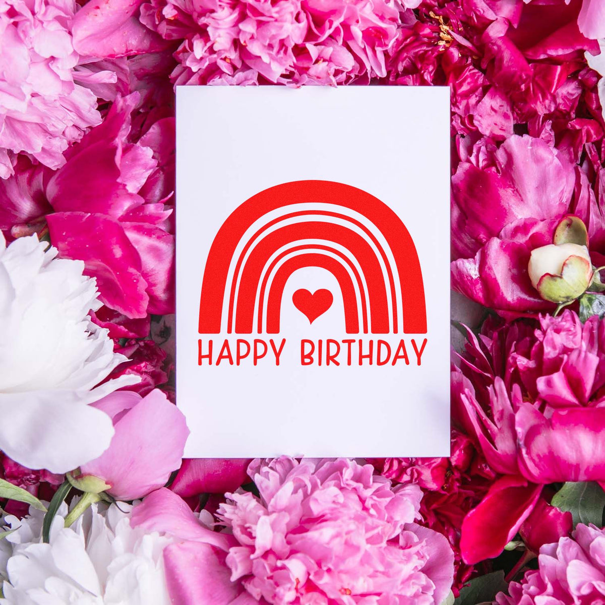 Red rainbow heart Happy Birthday stamp and seal on white card, surrounded by pink and white flowers.