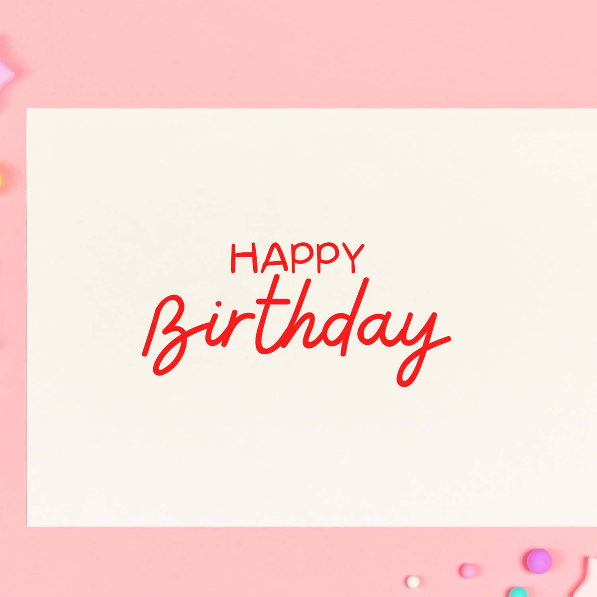 Red Happy Birthday stamp on cream card with pink background and small colorful wax seals.