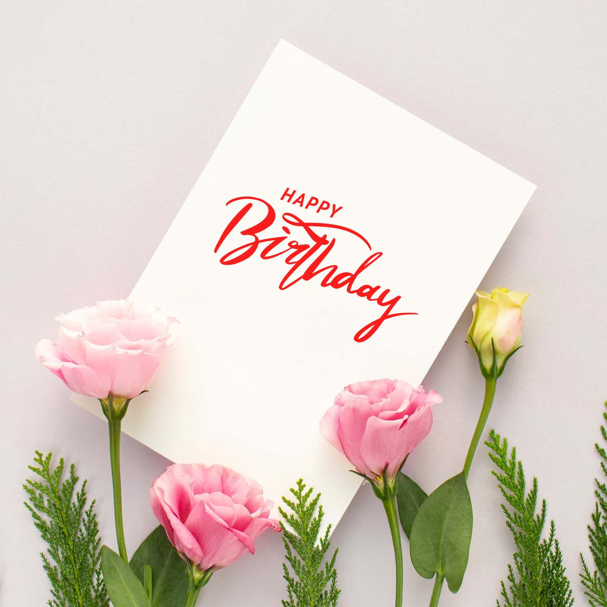 Red Happy Birthday stamp/seal on white card, framed by pink roses and green foliage.