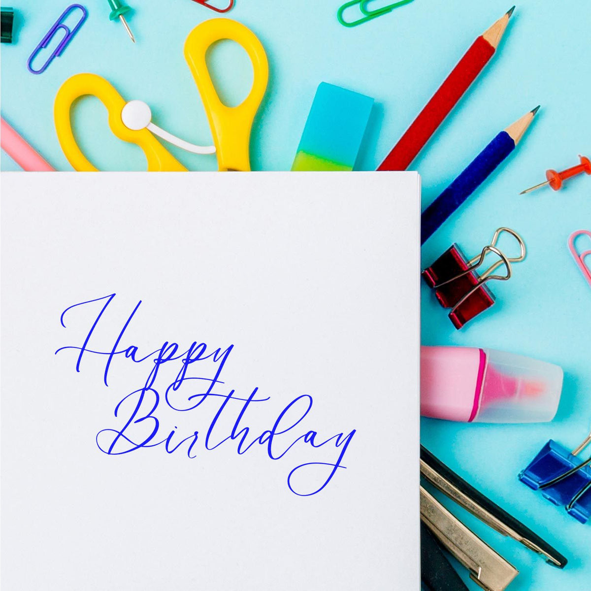 White birthday card with blue cursive text, surrounded by colorful stamp and seal products on a turquoise background.