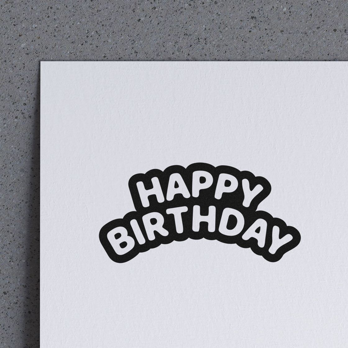 Black and white Happy Birthday stamp and seal on white paper, with bold arched lettering.